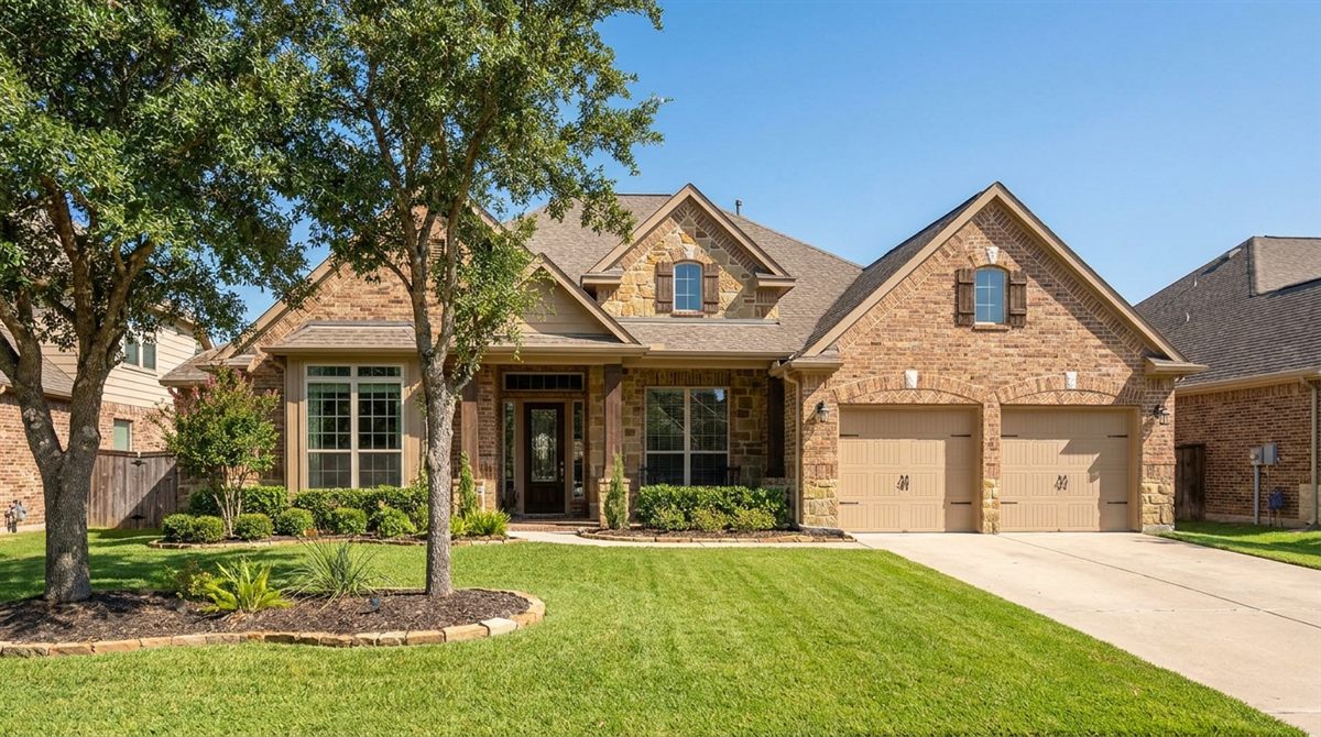 Bright, well-kept brick single-family home with a green lawn under a clear blue Texas sky, representing the type of Houston and Dallas property cash buyers compete for